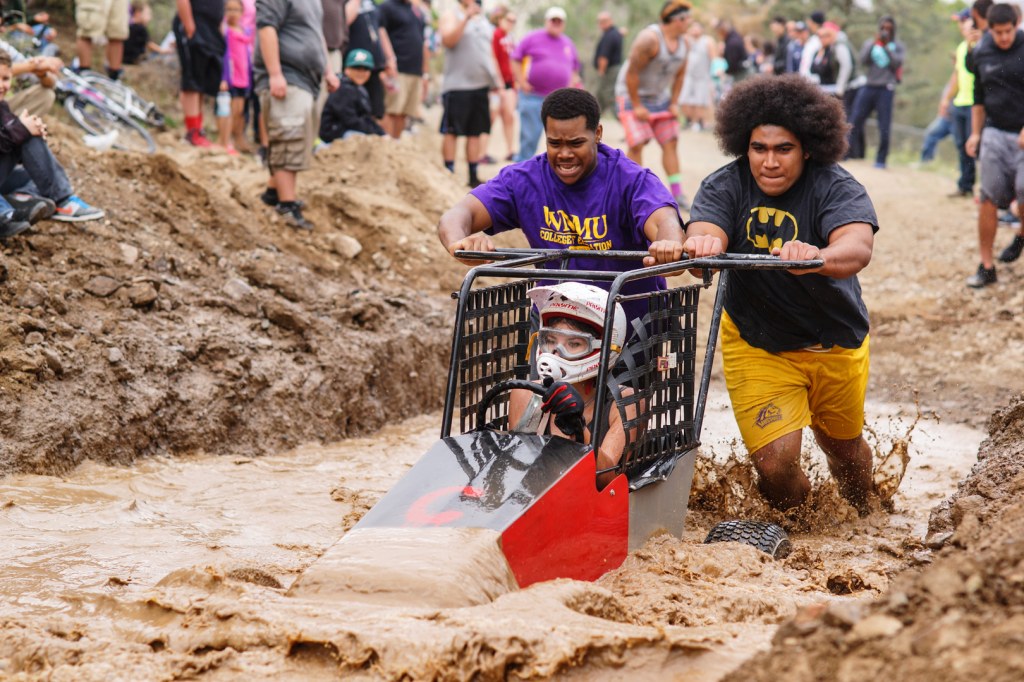 Students pushing one of our Great Race cars through a mud pit